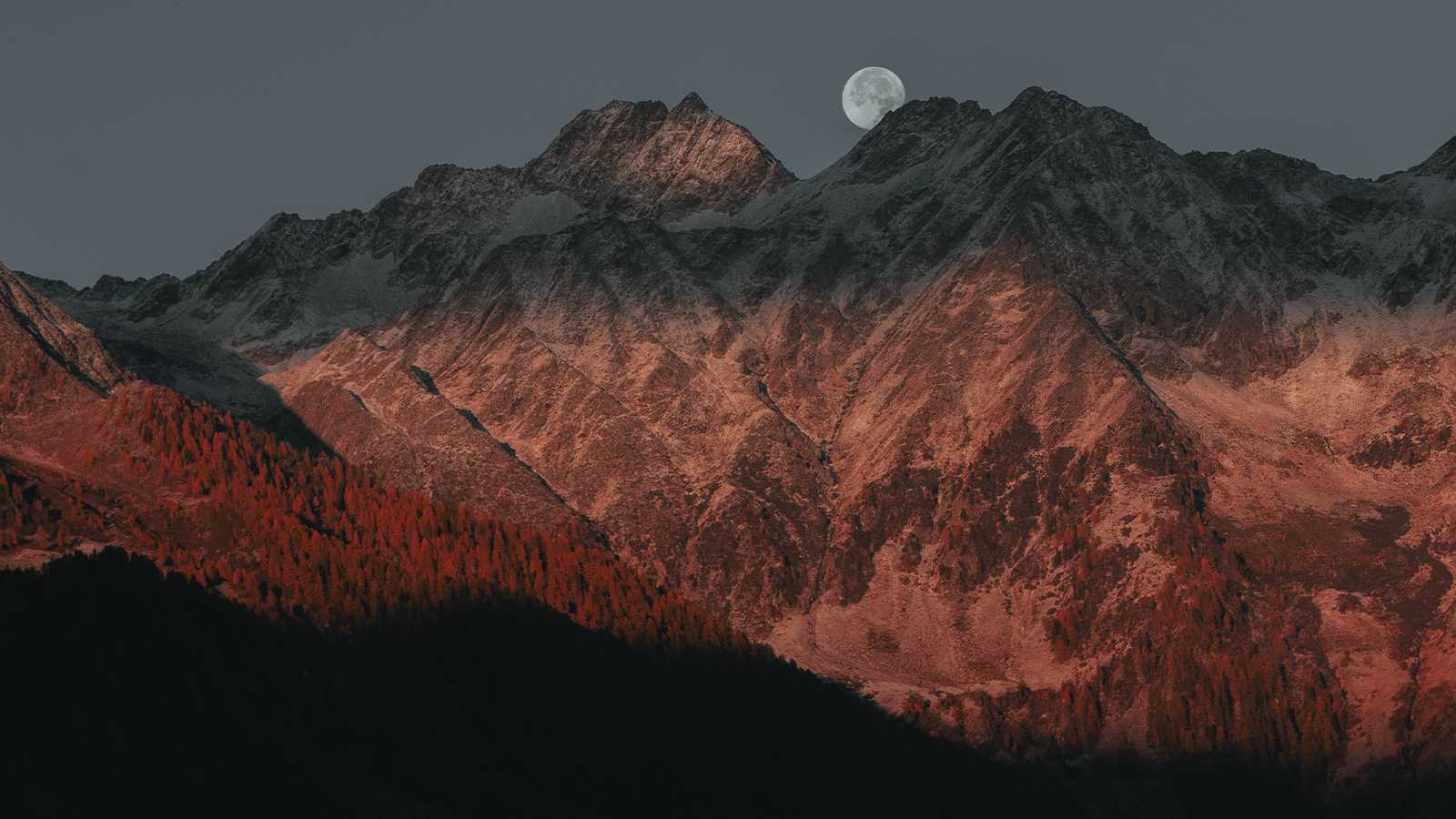 A full moon behind mountains