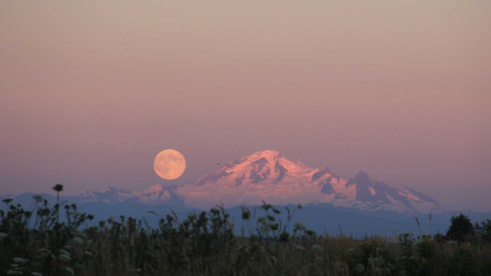 An orange moon above a mountain range