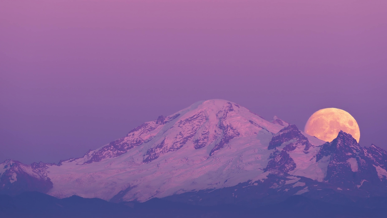 A full moon behind mountains